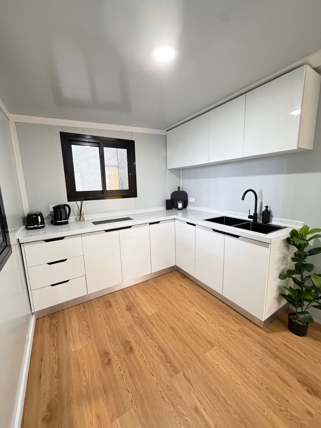 L-shaped kitchen with gloss white cabinetry, stone-look benchtop and black tapware