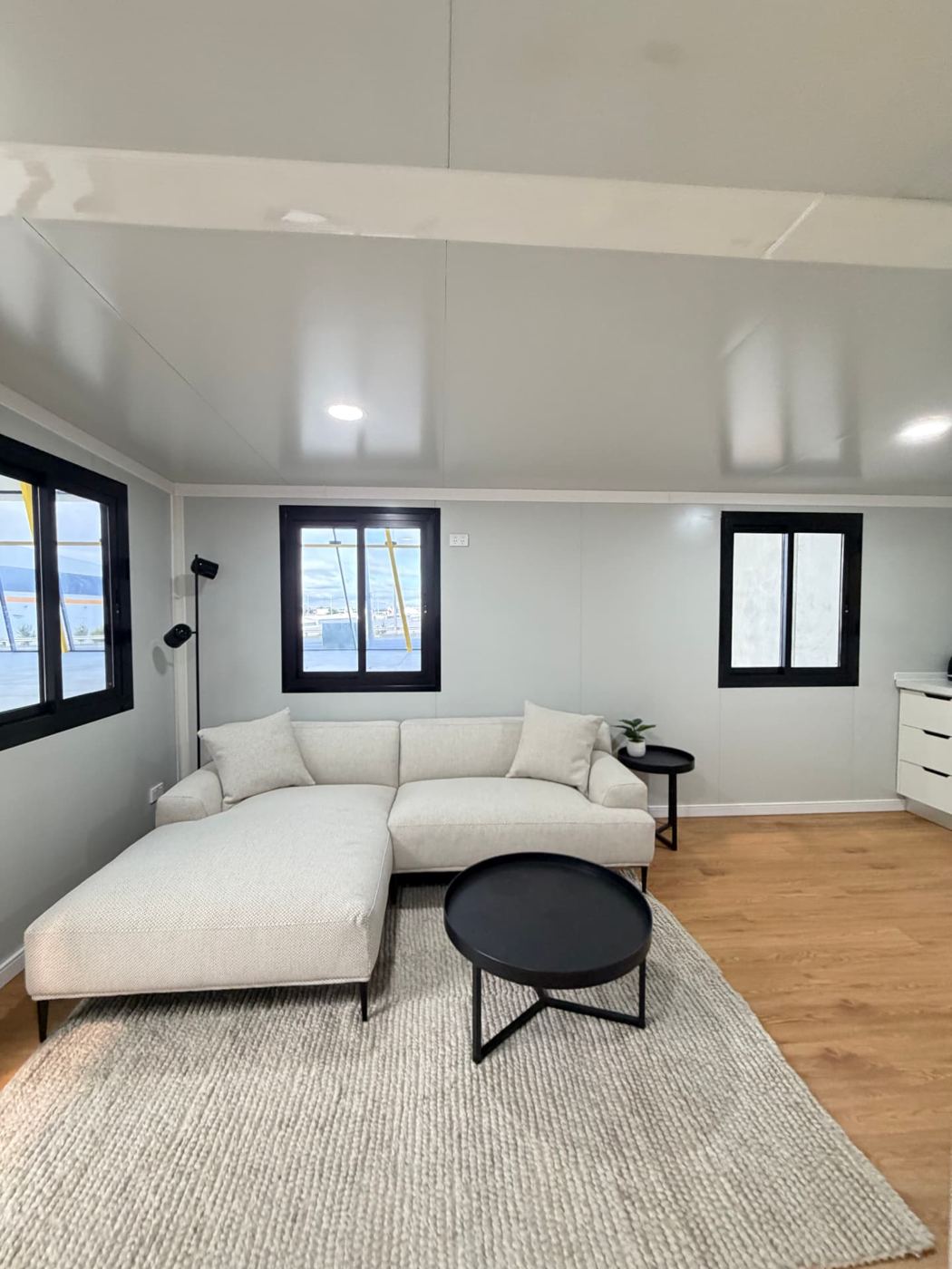 Lounge with L-shaped sofa, wool rug and black-framed sliding windows